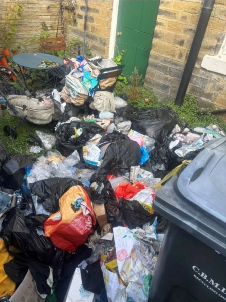 Back yard piled with bags of rubbish before the clearance